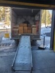 A moving truck loaded with boxes and large bags, with its ramp lowered.