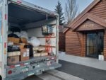 Boxes and bags in an open moving truck beside a lodge entrance.