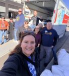 A group posing beside a moving truck.