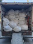 The back of a moving truck filled with white bags.