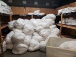 White bags stacked between shelves of folded linens.