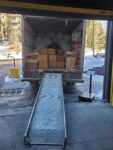 Boxes and bags packed inside a moving truck with an open loading ramp.